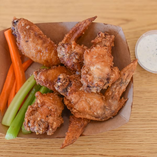Crispy fried chicken wings with carrot and celery sticks, and a side of ranch dressing.
